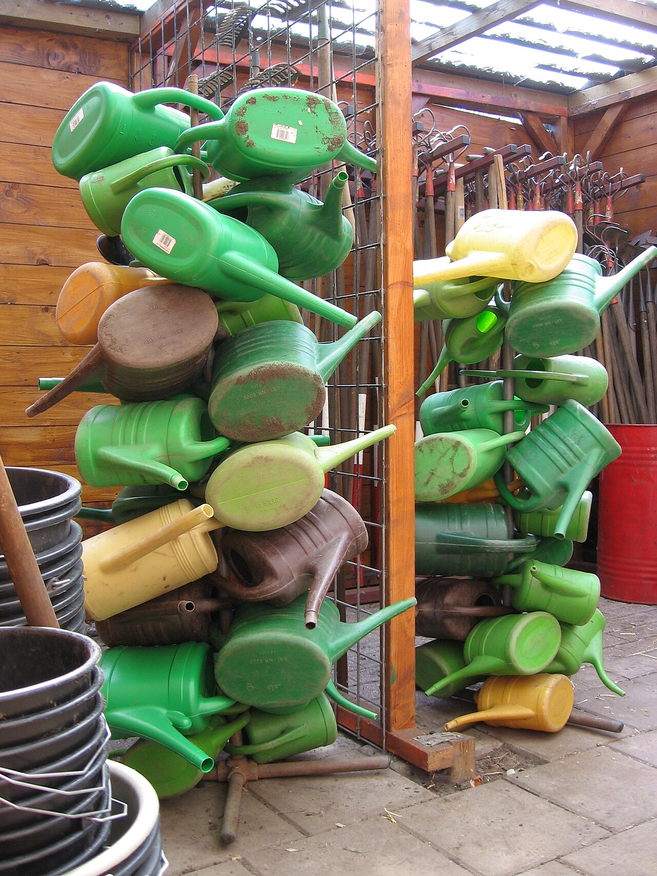Watering cans stored beside long-handled tools inside a school garden's working shed